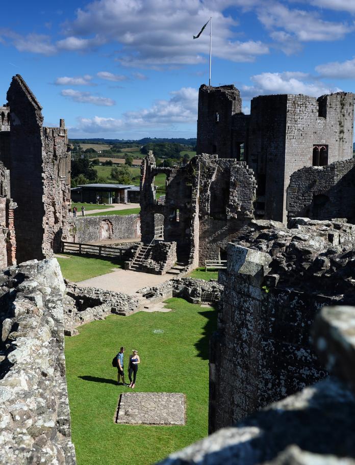 Image of Raglan Castle from above, with two people walking through the ruins