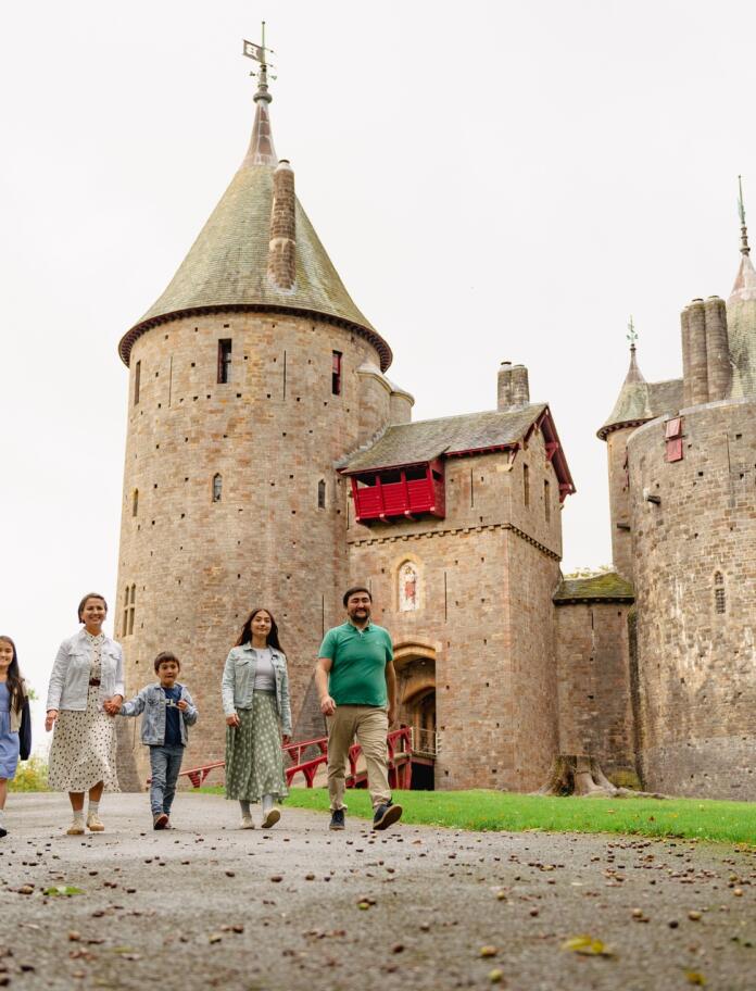 family walking outside castle with turrets.