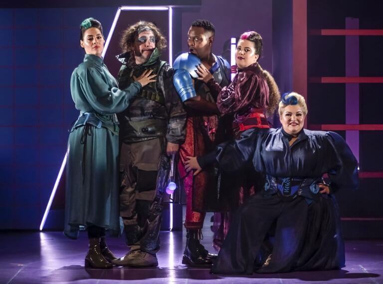 A group pf opera singers in dystopian outfits posing on stage