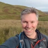 Matthew Yeomans standing in a large green mountainous landscape