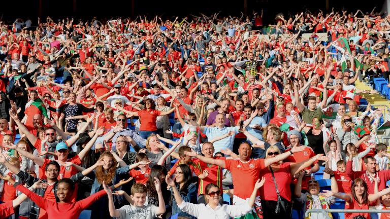 A crowd of people at a football game singing the national anthem.