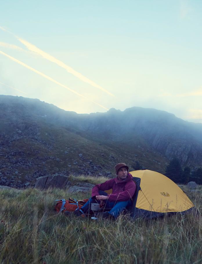 Richard Parks sentado fuera de su tienda de campaña, camping en país de Gales