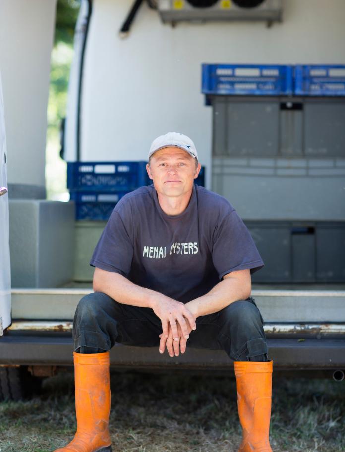 Shaun Krijnen of Menai Oysters sitting in the back of a van.