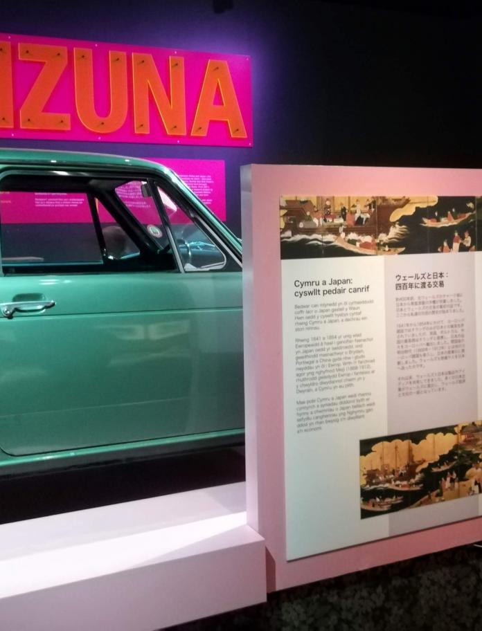 Une voiture verte et un tableau d’affichage à l’exposition Kizuna