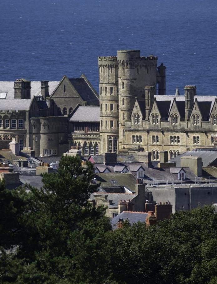 The gothic style Old College building in Aberystwyth with the sea in the background.