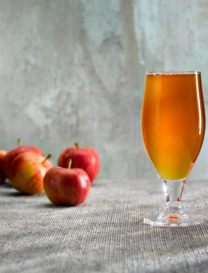 リンゴの隣に置かれたアップルサイダーの入ったグラス