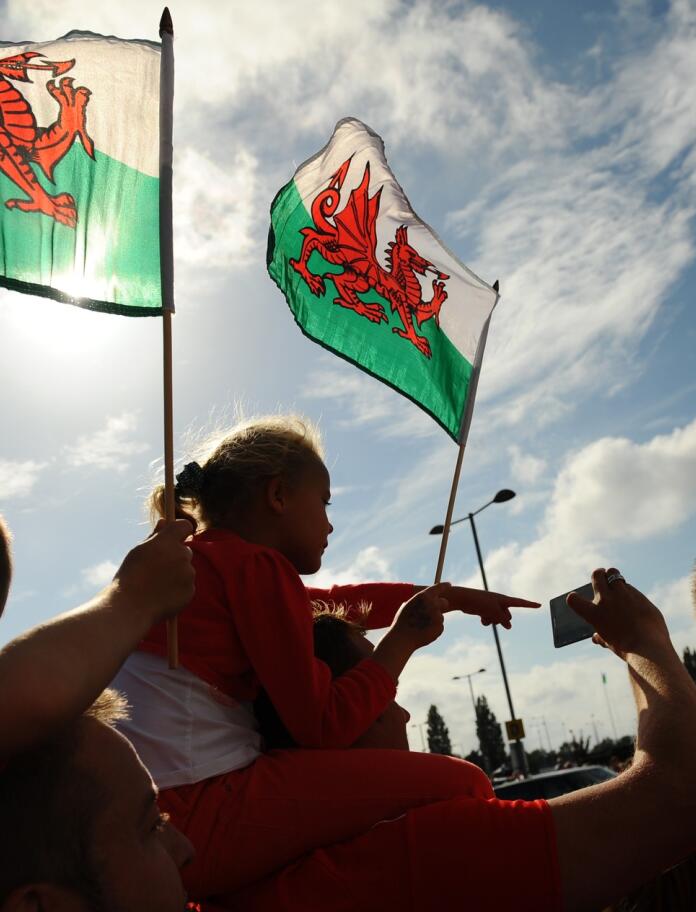 La silueta de tres personas sosteniendo banderas galesas.