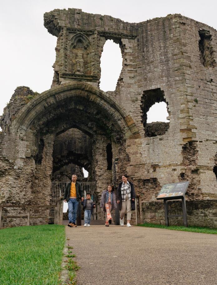 familia caminando cerca de un arco en ruinas de un castillo.