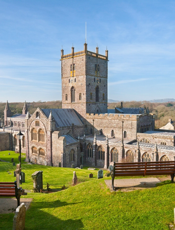 A stone cathedral surrounded by grass and grave stones.