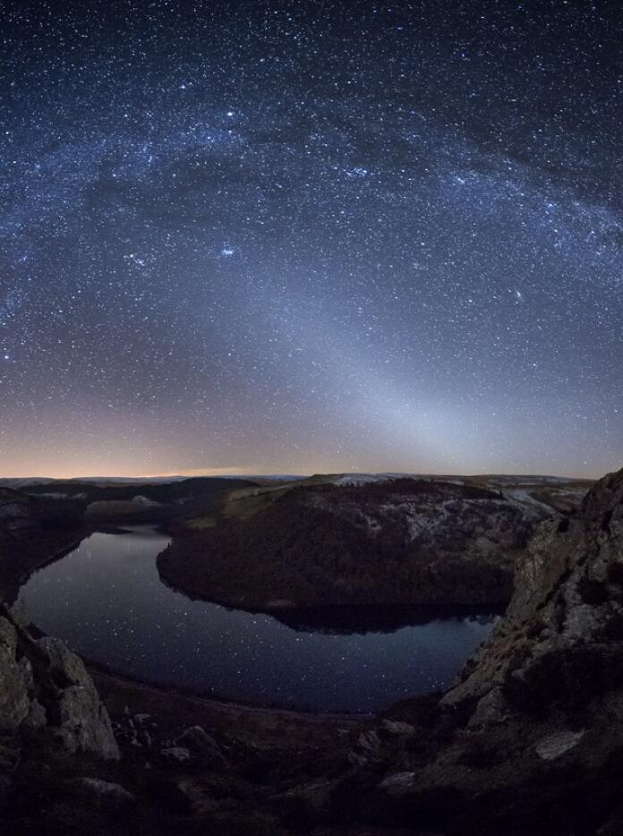 Photo de nuit d'une vallée avec un lac et un ciel étoilé.