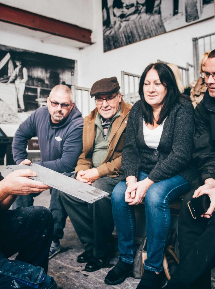 Un groupe de visiteurs apprend à fendre l'ardoise.