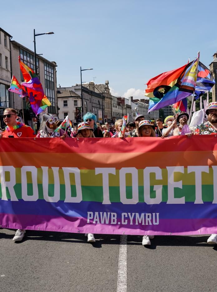 Un grupo de seguidores LGBTQIA+ llevando una pancarta arcoíris que dice Orgullosos Juntos