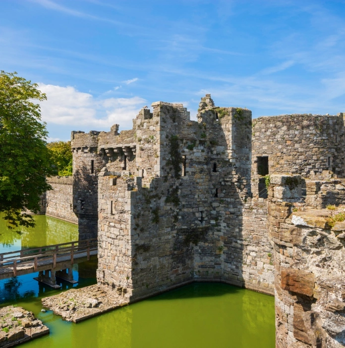 Un grand château ancien avec des douves sur fond de ciel bleu.