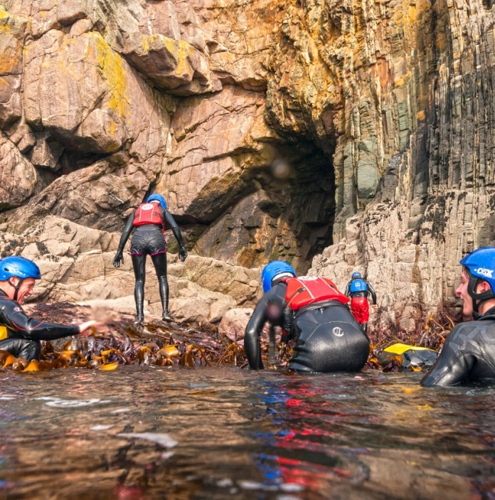 Un groupe de personnes qui portent un équipement de sécurité aquatique dans l'eau, près de la côte.