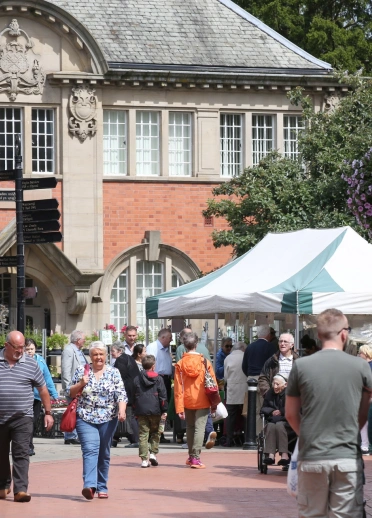 People walking through the market stalls in the town centre.