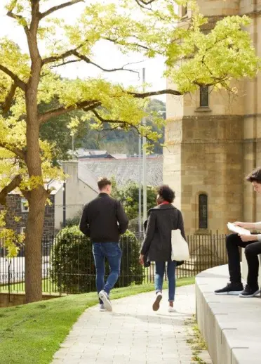 Two people walking and one sat on steps Bangor University