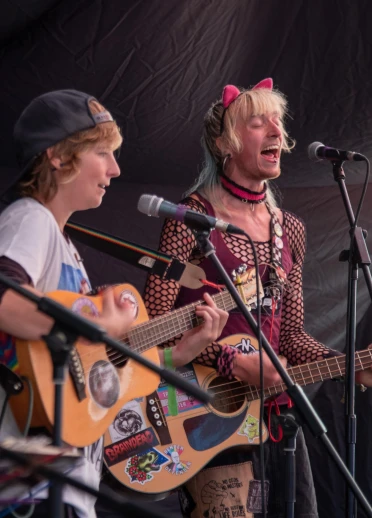 Zwei Personen, die Gitarre spielen und auf der Bühne singen.