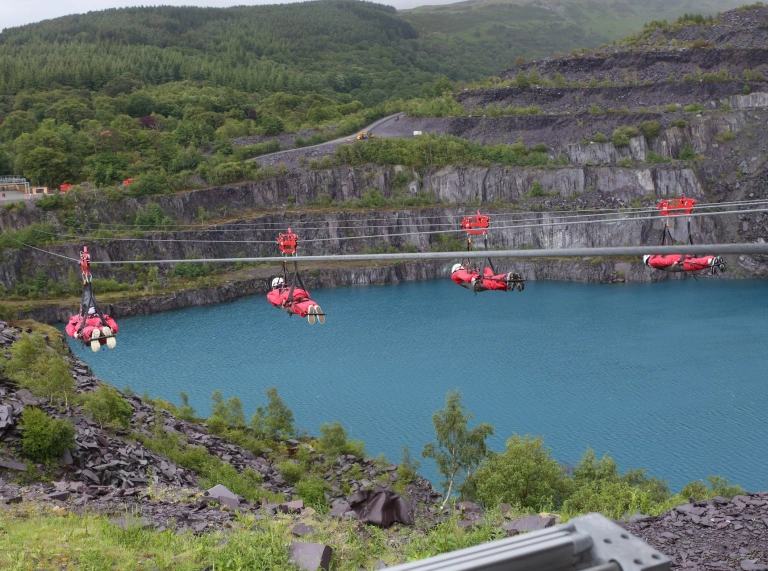 4 people on a zip wire over water.