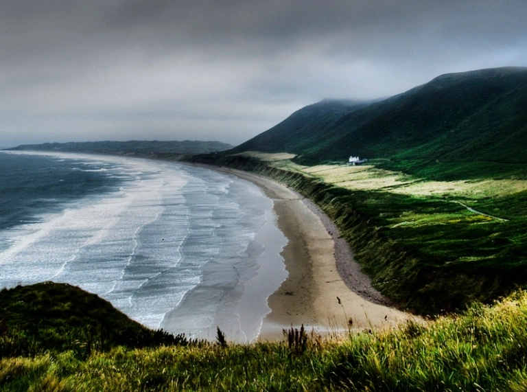 A view of Rhossili beach from above with sand and the sea.