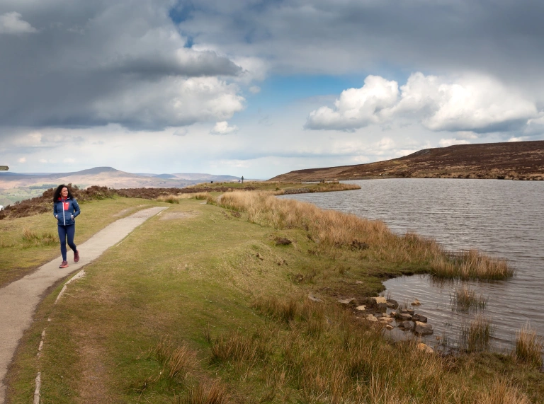 A women walking along a path next a lake.