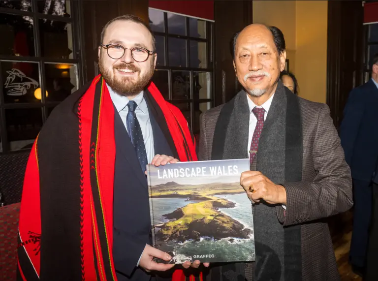 Two men smiling at camera holding up Landscape Wales book