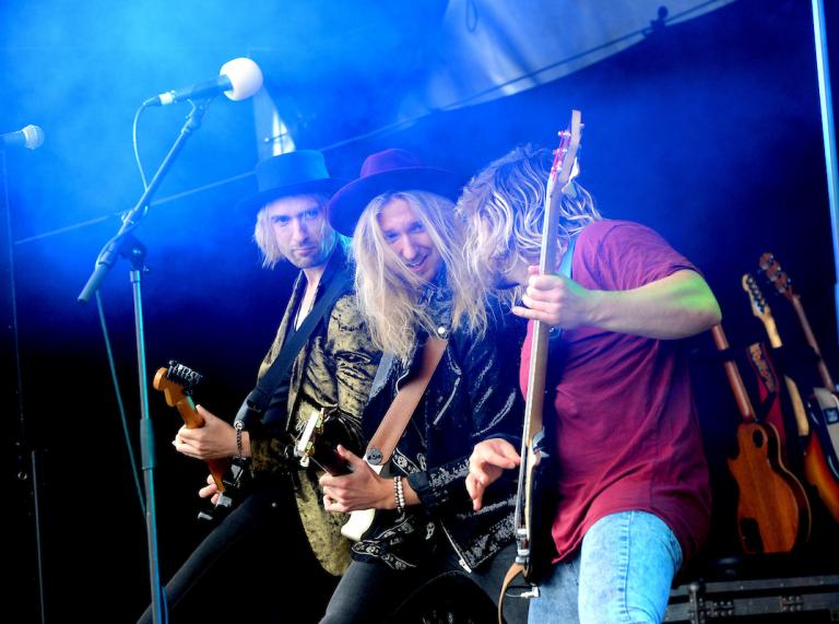 Tres hombres tocando la guitarra en el escenario.
