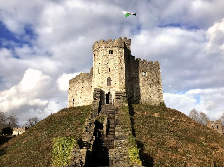 Donjon normand au sommet d'un monticule vert et herbeux, avec le drapeau gallois qui flotte au sommet.