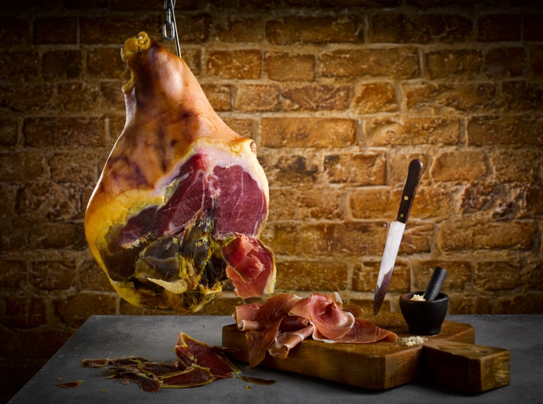 フックにかかったハムとスライスしたハムの横にあるナイフ