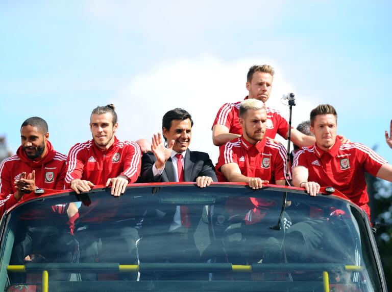 L'équipe de football du Pays de Galles sur le toit de leur bus touristique saluant la foule en dessous.