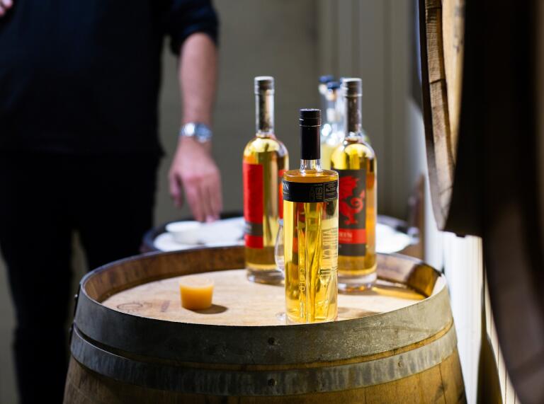 Bouteilles de whisky Penderyn disposées décorativement sur un vieux tonneau de whisky