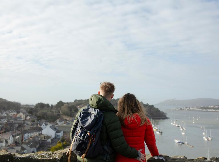 Two people looking over the castle walls to the sea.