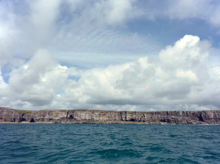 Blue sea and cliffs in the distance (as seen from a boat)