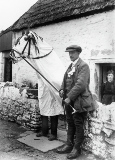 A Mari Lwyd and a man outside a cottage