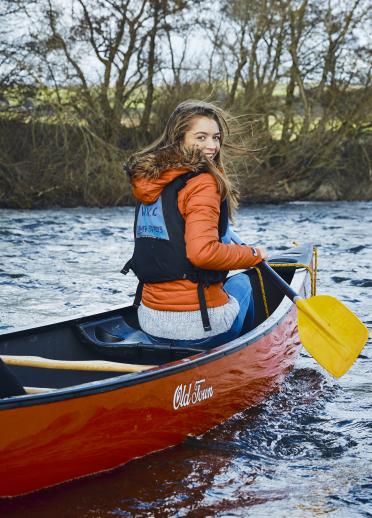 Una mujer joven sentada en una canoa en un río.