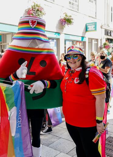 Tracy Brown à la marche Pride Cymru portant le maillot du Pays de Galles à côté de la mascotte Urdd