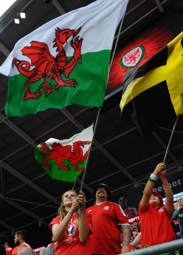 Personas sosteniendo la bandera galesa sobre sus cabezas.