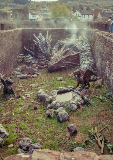 looking down into castle with dragon sculptures and in the background a man looking over the wall