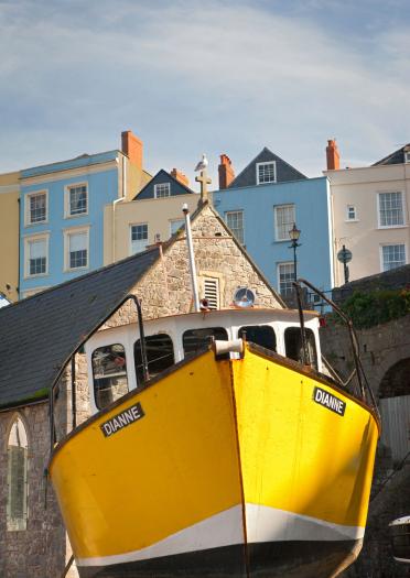 Bateau jaune dans le port à marée basse dans les maisons colorées de Tenby en arrière-plan