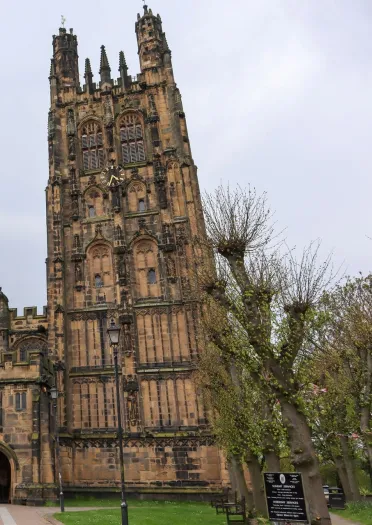 A large very old church with tall tower set in a large green church ground