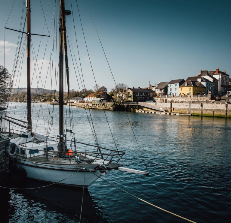 A boat on the water with rows of colourful houses in the background.