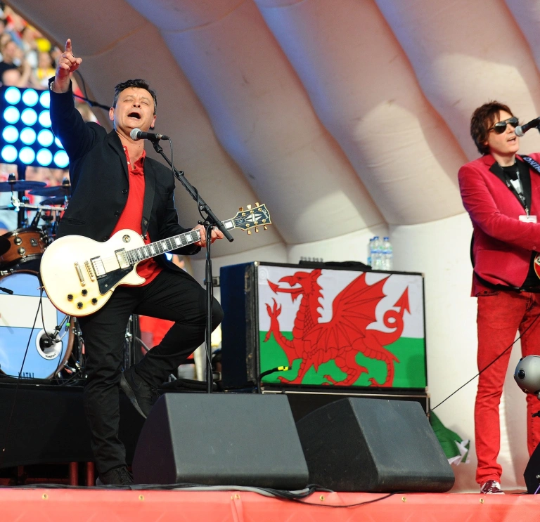 Two people playing guitars and singing on a stage.