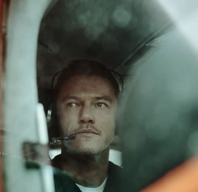 Luke Evans mit einem Headset in einem Kleinflugzeug, bereit zum Abflug