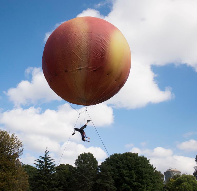 Ein pfirsichfarbener Ballon mit einem Künstler darunter
