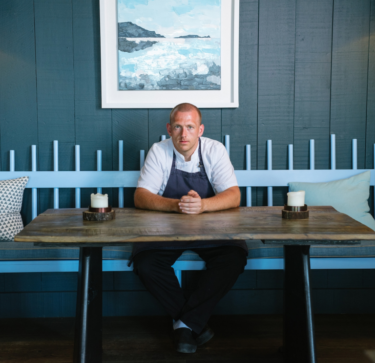 Hywel Griffith assis à une table de son restaurant, Beach House.