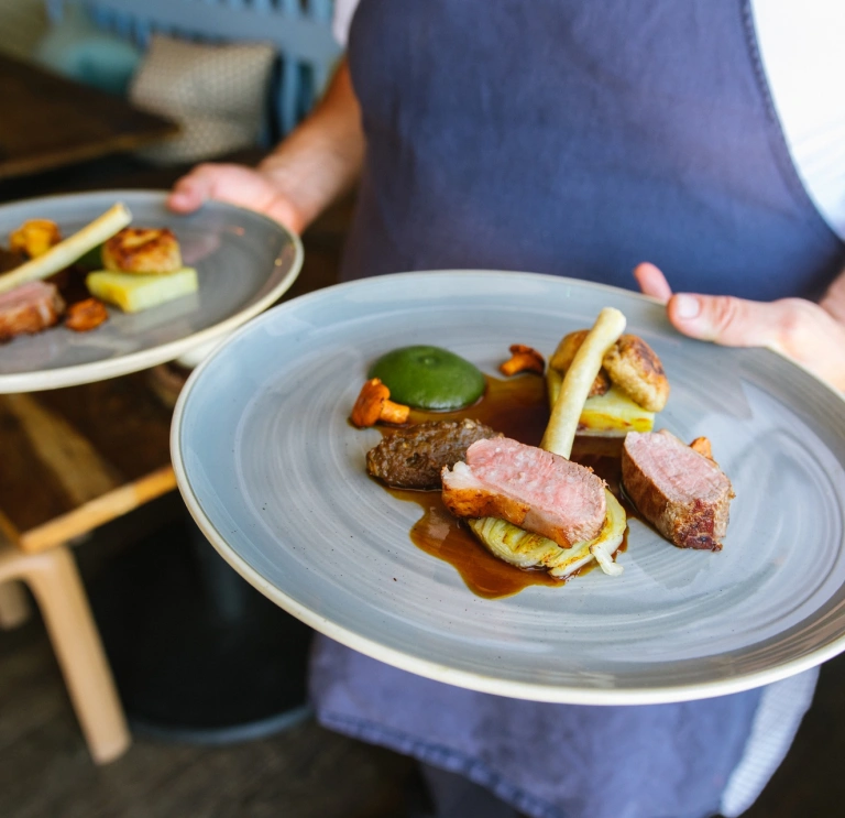 Un chef que lleva dos platos de comida.