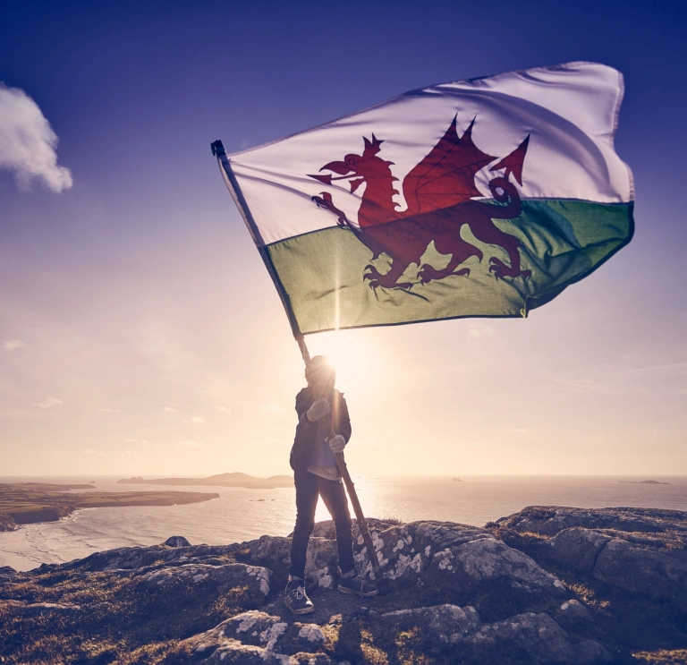 Person, die die Flagge von Wales hält.