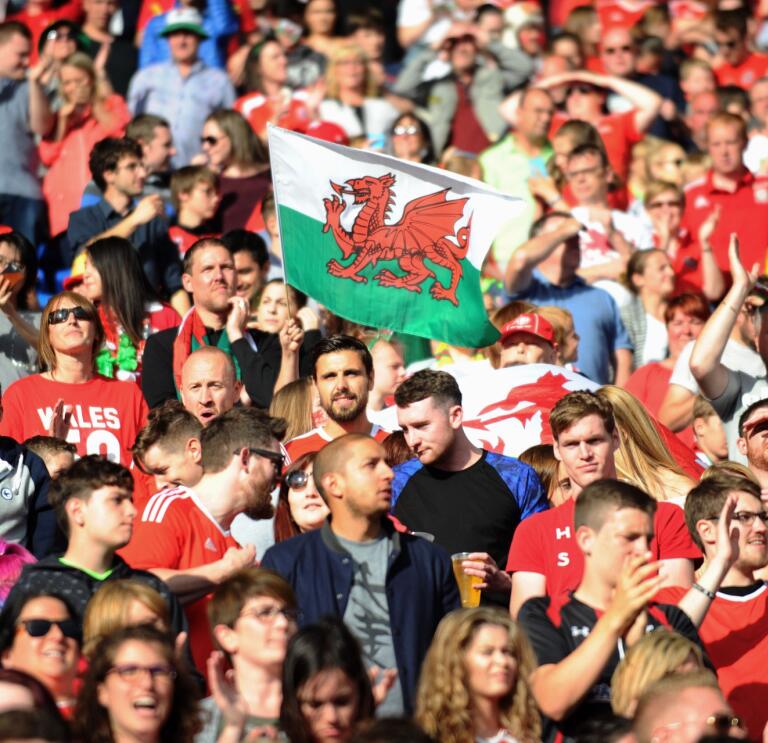 Una multitud de personas y una bandera galesa.