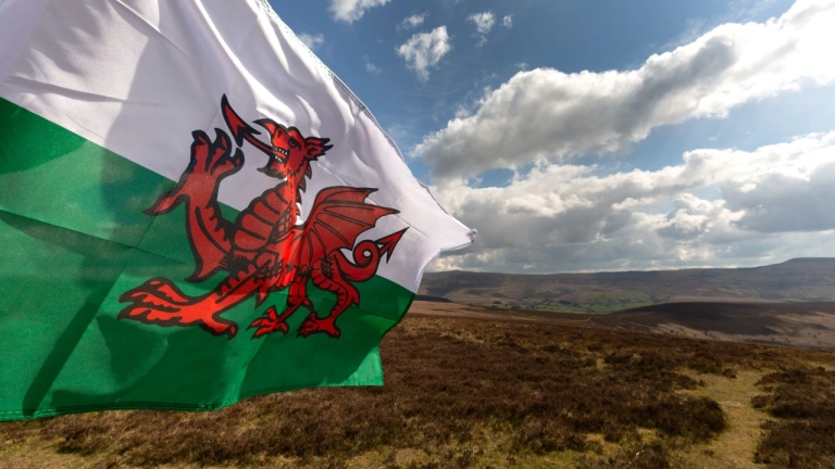 A Welsh flag blowing in the wind across a beautiful mountainous moorland scene