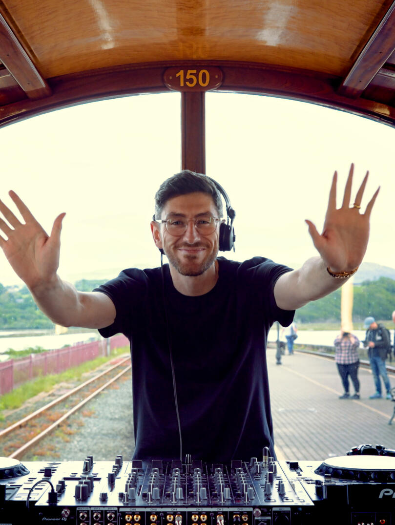 A man DJing at the back of a train.