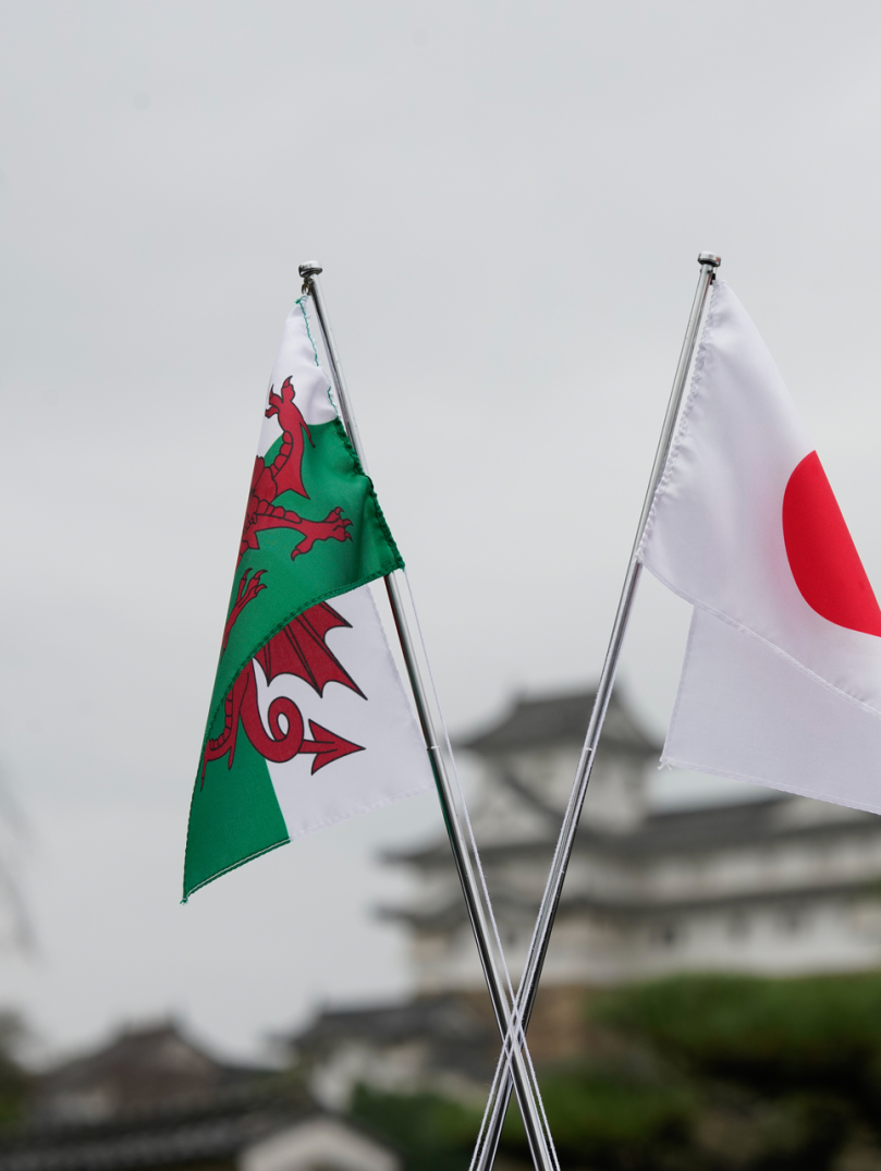 Eine walisische und eine japanische Flagge vor der Burg Himeji.